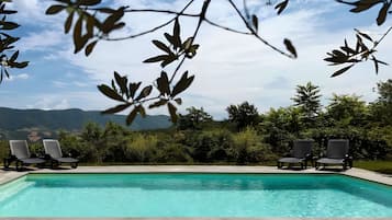 A swimming pool with lounge chairs and a view of mountains.