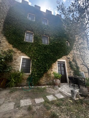 A stone building with ivy-covered walls, a door, and windows. - Apartment 'Rinascita - Dimore Del Castello' with Mountain View, Shared Pool and Wi-Fi (Gualdo Cattaneo)