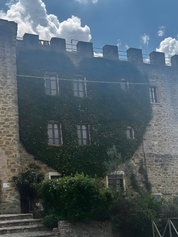 A stone building with ivy-covered walls and multiple windows. - Apartment 'Rinascita - Dimore Del Castello' with Mountain View, Shared Pool and Wi-Fi (Gualdo Cattaneo)