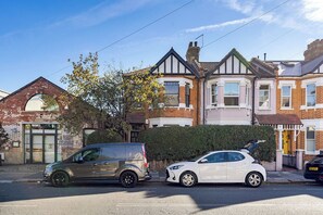 A residential street with two cars parked on the side. - Kensal Rise Garden Oasis, by Veeve (London)