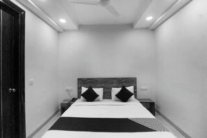 A bedroom with a bed, two nightstands, a ceiling fan, and a door.