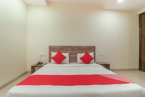 A hotel room with a bed, two nightstands, a red and white bedspread, and a wooden headboard.
