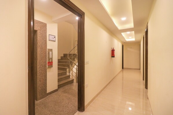 A hallway with a staircase, a fire extinguisher, and a sign indicating the lift main.