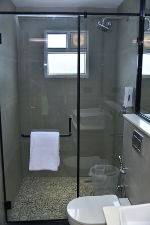 Une cabine de douche moderne dotée d’une porte en verre, d’un porte-serviettes et d’un pommeau de douche.