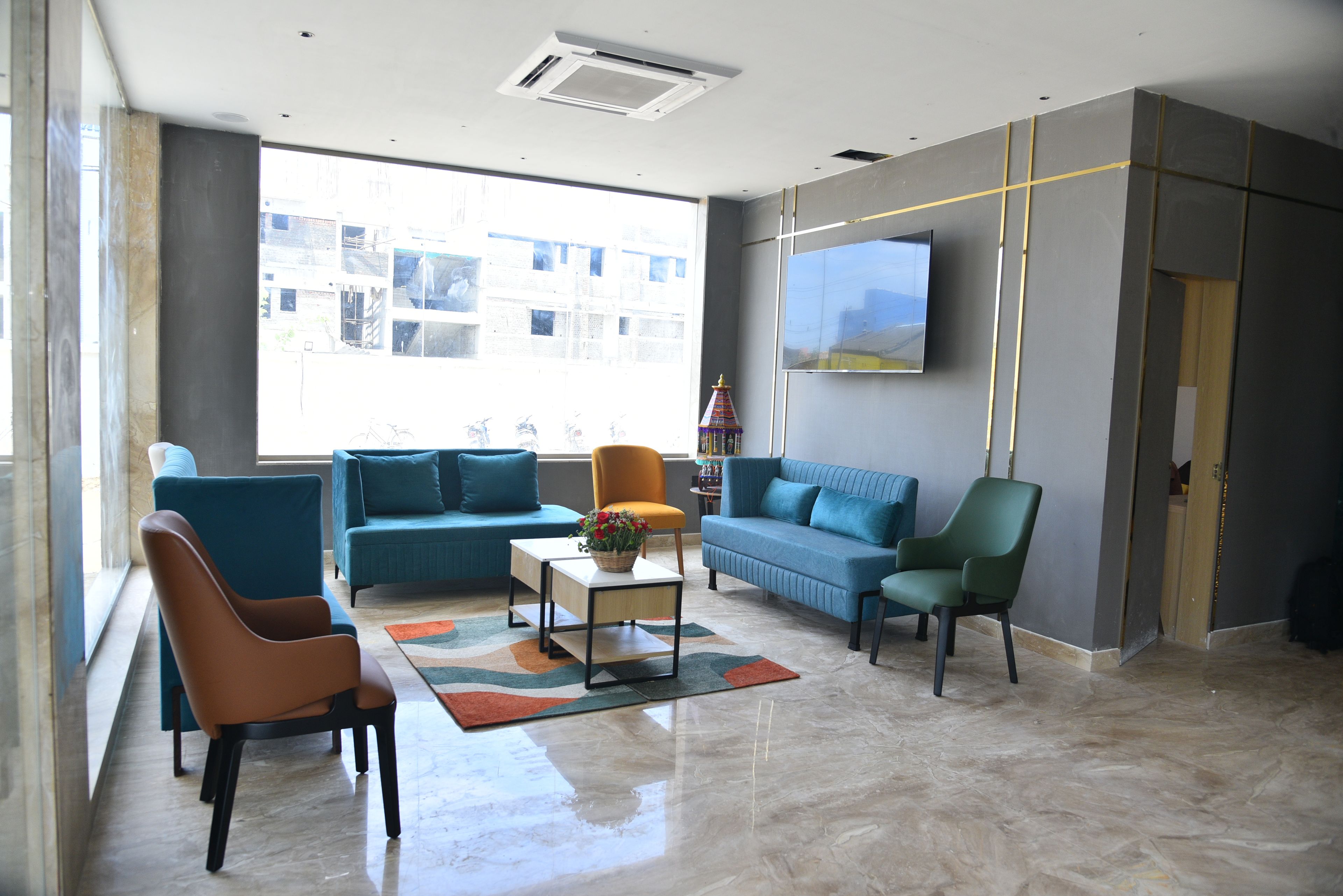 Una sala de estar moderna con un sofá, sillas, una mesa de centro y un televisor montado en la pared.
