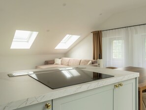 Eine moderne Küche mit einer eleganten Arbeitsplatte und integriertem Herd, eine gemütliche Sitzecke mit einer Couch und ein großes Fenster für natürliches Licht.