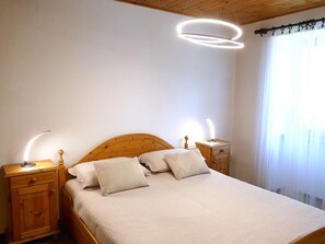 Ein Schlafzimmer mit einem hölzernen Bett, zwei Nachttischen und einer modernen Deckenleuchte.