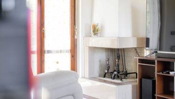 Un salon avec une cheminée, un téléviseur et une porte donnant sur l’extérieur.