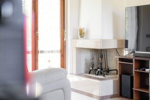 Un salon avec une cheminée, un téléviseur et une porte donnant sur l’extérieur.