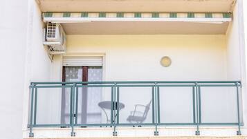 Un balcon avec une balustrade en métal, une petite table et une chaise.