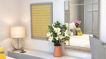 A modern bedroom with a bed, bedside table, lamp, mirror, and decorative items.