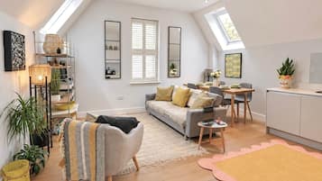 Eine moderne Loft-Wohnung mit hohen Decken, Dachfenstern, einer Essecke, einem Sofa, einer Küche und einem Wohnbereich.