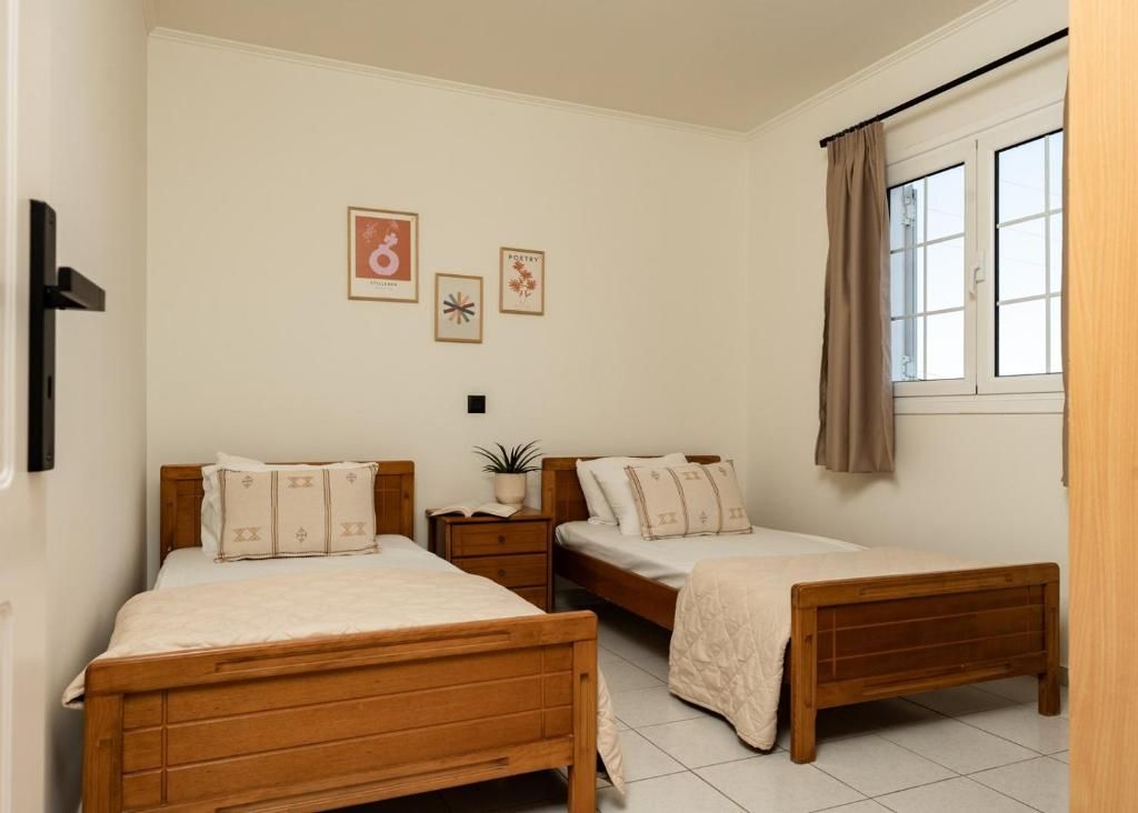 Een slaapkamer met twee houten bedden, een nachtkastje met een plant en een raam met gordijnen.