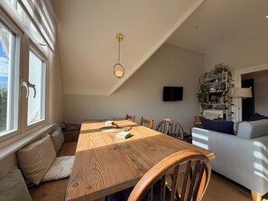 A dining area with a wooden table, chairs, and a ceiling light fixture. - Beautiful 1BDR Hideaway in West Hampstead (London)