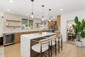A modern kitchen with a central island, bar stools, pendant lighting, and a large mirror. - This house is a 3 bedroom(s), 2 bathrooms, located in Tempe, AZ. (Tempe)