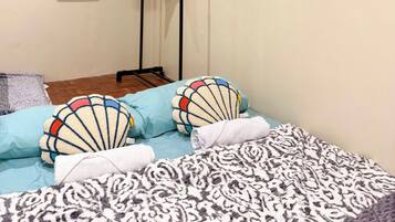 A bedroom with a bed, pillows, a hanging clothes rack, a window, and a mirror.