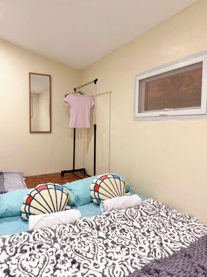 A bedroom with a bed, pillows, a hanging clothes rack, a window, and a mirror. - INARI SORA Soothing Studio Newly Built Guesthouse in LU (San Juan)