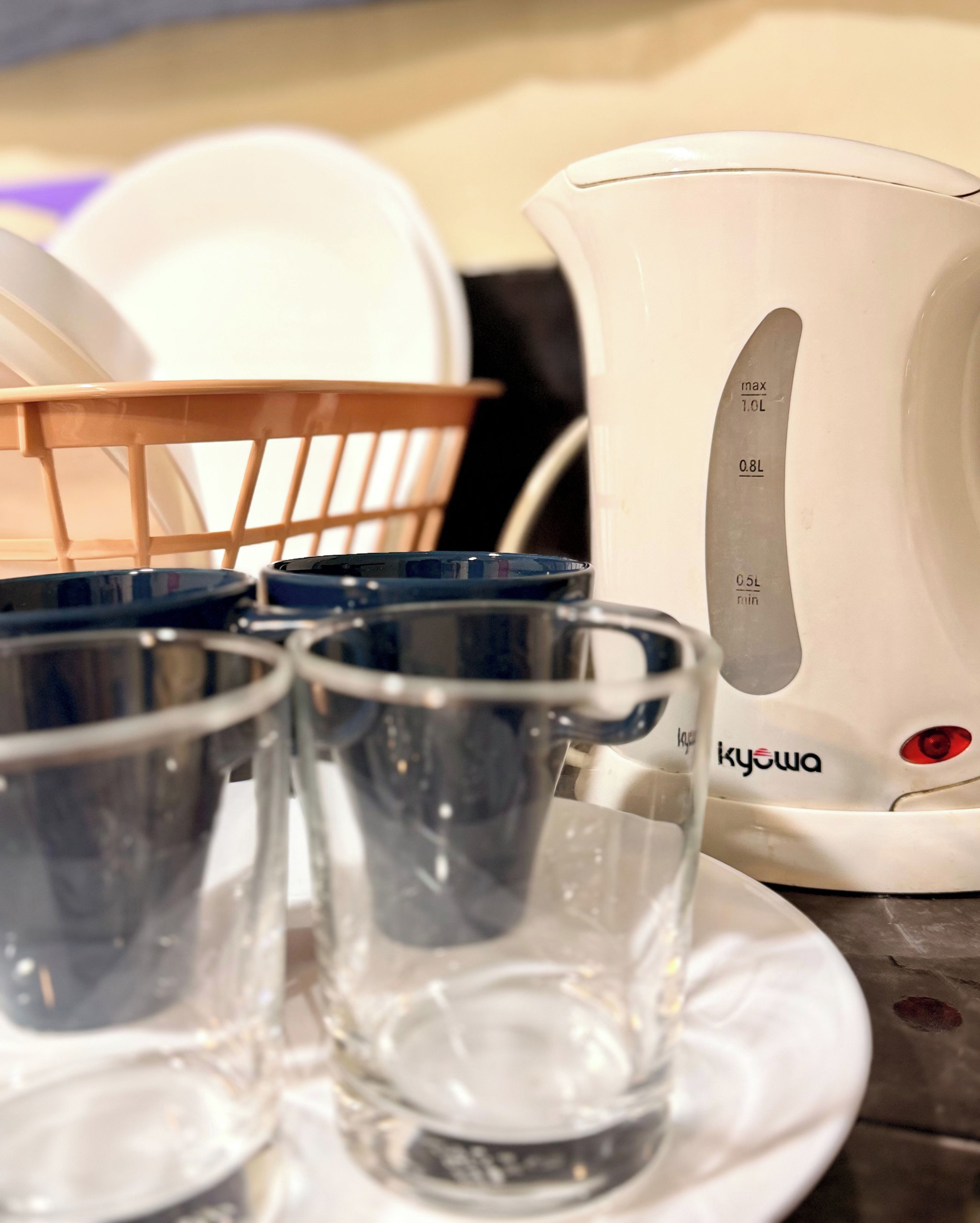 Una tetera eléctrica blanca con marcas de medición y el nombre de la marca 'kyowa' sobre un plato blanco.