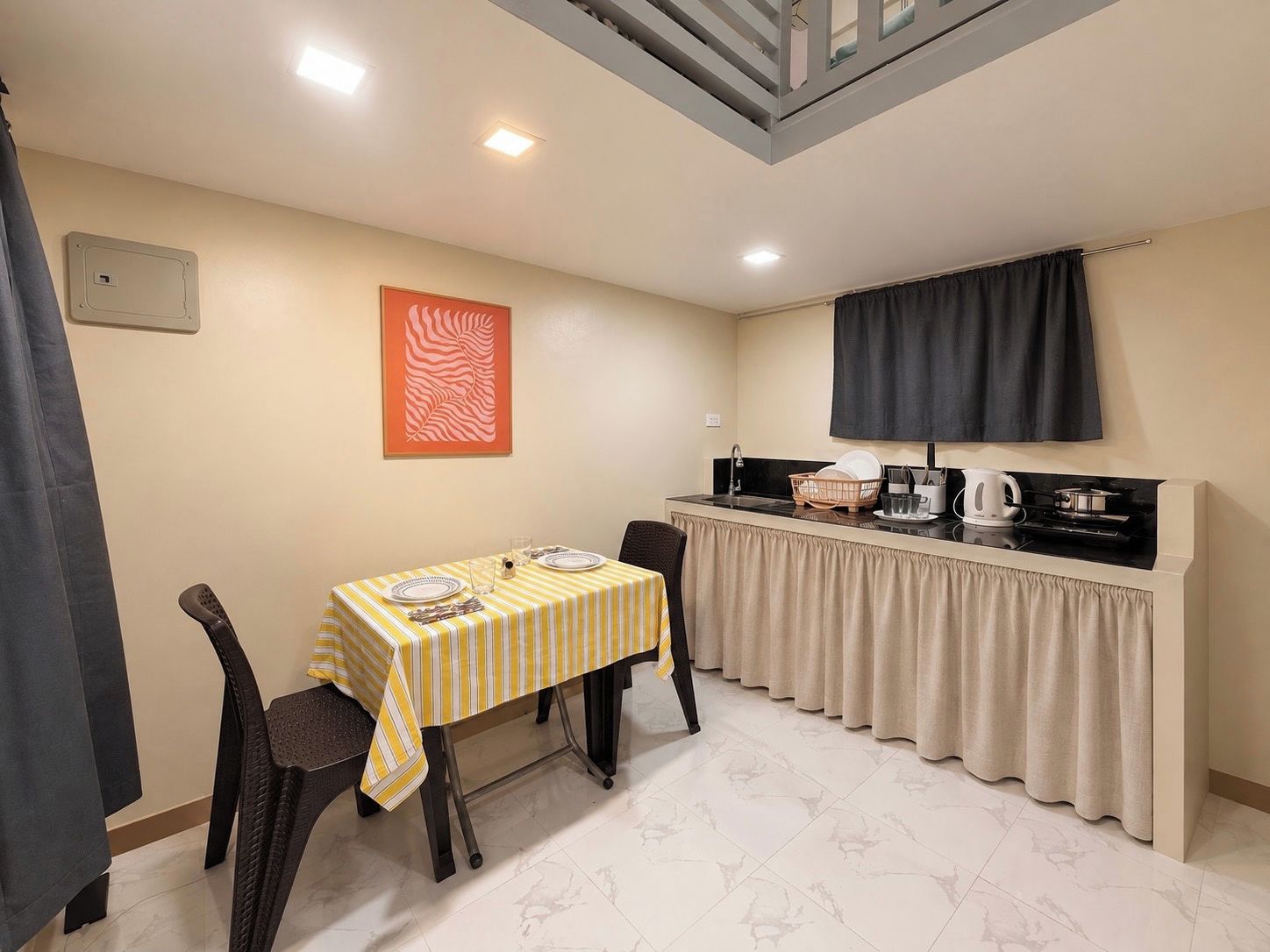 A compact kitchen with a dining area, featuring a striped tablecloth, chairs, a stove, and a sink.