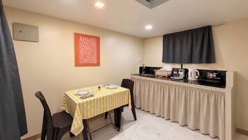 A compact kitchen with a dining area, featuring a striped tablecloth, chairs, a stove, and a sink.