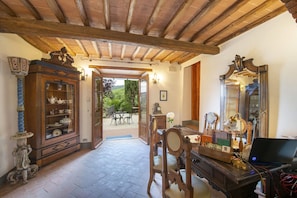 A room with a wooden ceiling, a cabinet with glass doors, a desk with a laptop, and a mirror. - Villa Grevigiana 12 pool and SPA - My Rental Homes (Panzano In Chianti)