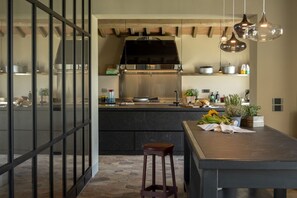 A modern kitchen with a central island, a dining area with a wooden table, and a bar stool. - Villa del Re with swimming pool - My Rental Homes (Monte Del Lago)