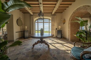 Ein geräumiges Zimmer mit Steinböden, einem runden Tisch und Meerblick durch große Fenster.