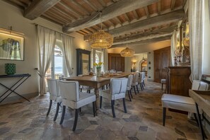 A spacious dining area with a large wooden table, multiple chairs, and a stone-tiled floor. - Villa del Re with swimming pool - My Rental Homes (Monte Del Lago)