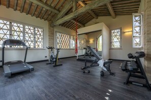 A gym with treadmills, an elliptical, a bench press, and dumbbells. - Villa del Re with swimming pool - My Rental Homes (Monte Del Lago)