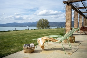 A patio with two green metal chairs, a wicker basket, and a table. - Villa del Re with swimming pool - My Rental Homes (Monte Del Lago)