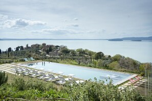 A pool area with lounge chairs and a view of a lake and buildings in the distance. - Villa del Re with swimming pool - My Rental Homes (Monte Del Lago)