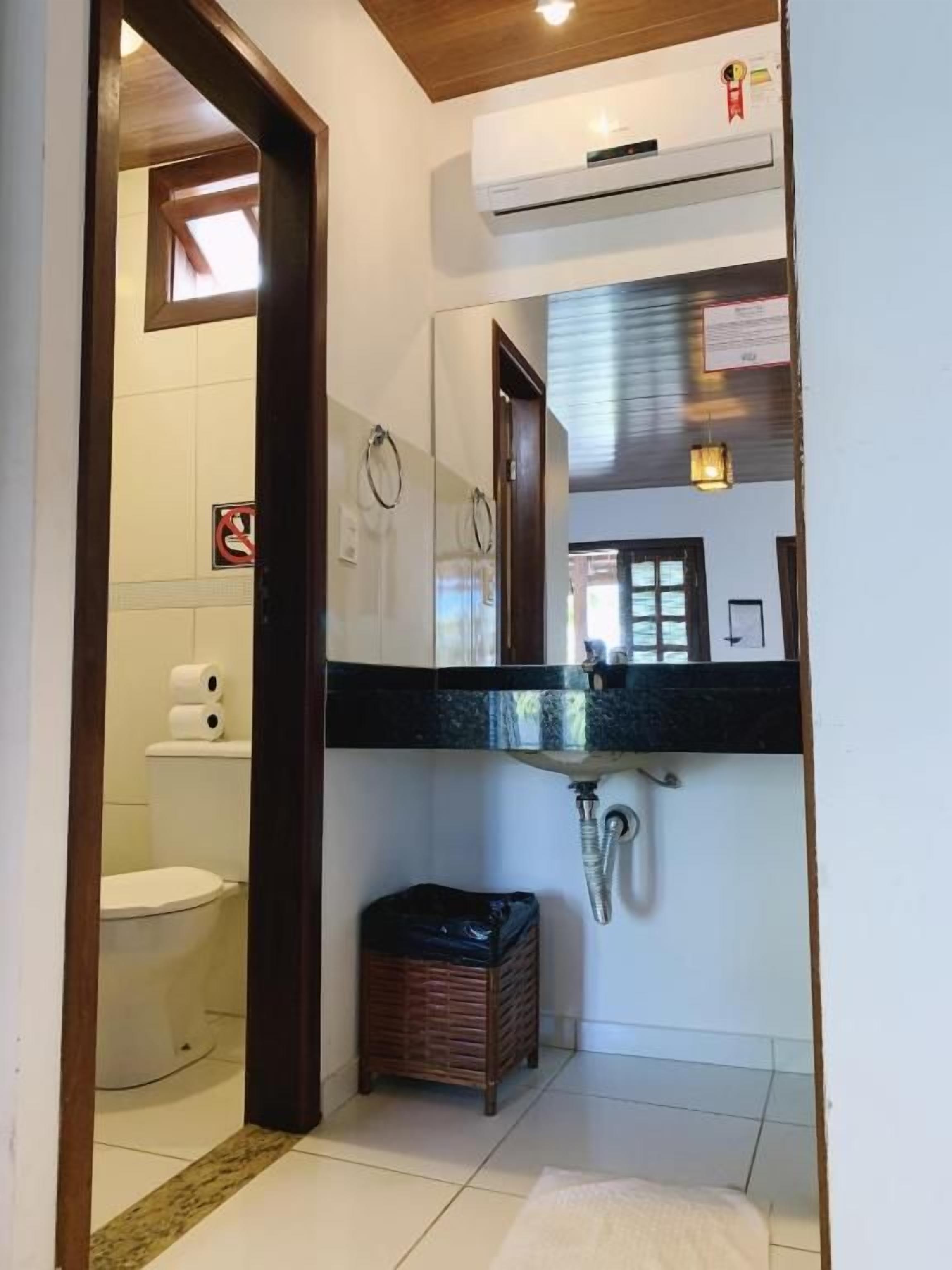 Une salle de bain avec des toilettes, un lavabo et un miroir.