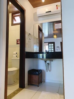 Een badkamer met toilet, wastafel en spiegel.