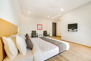 Una habitación de hotel con una cama, dos sillas, un televisor y una puerta.