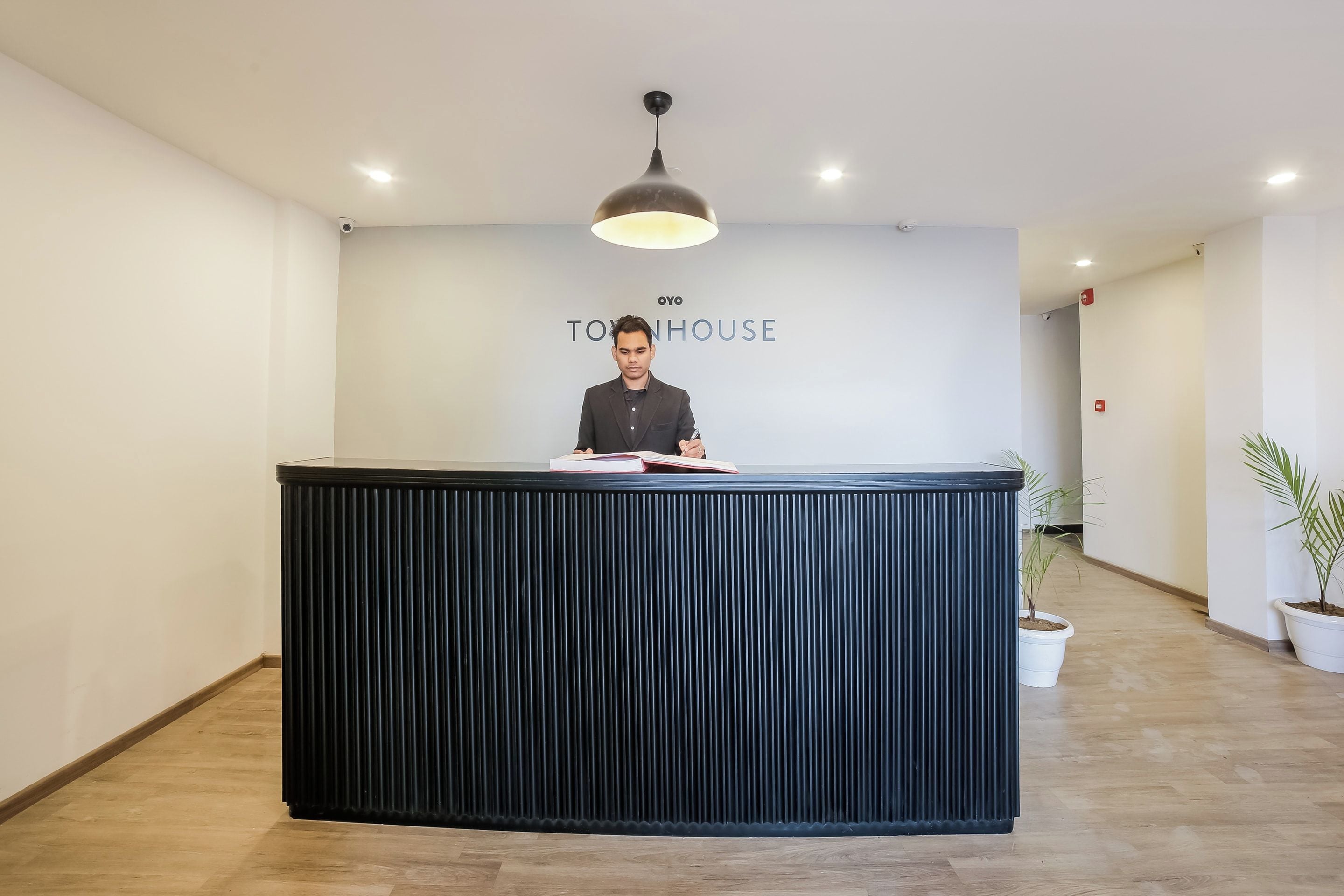 Een receptiebalie met een modern design, een plafondlamp en een bord met de tekst 'TOY HOUSE'.