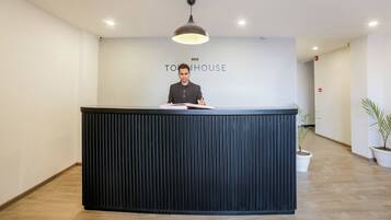 Een receptiebalie met een modern design, een plafondlamp en een bord met de tekst 'TOY HOUSE'.
