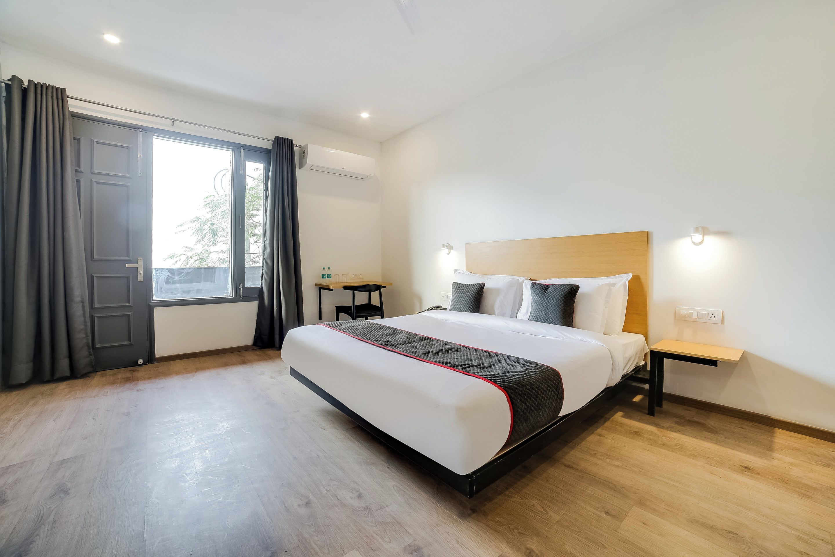 Une chambre d’hôtel moderne avec un grand lit, un bureau et une fenêtre avec des rideaux.