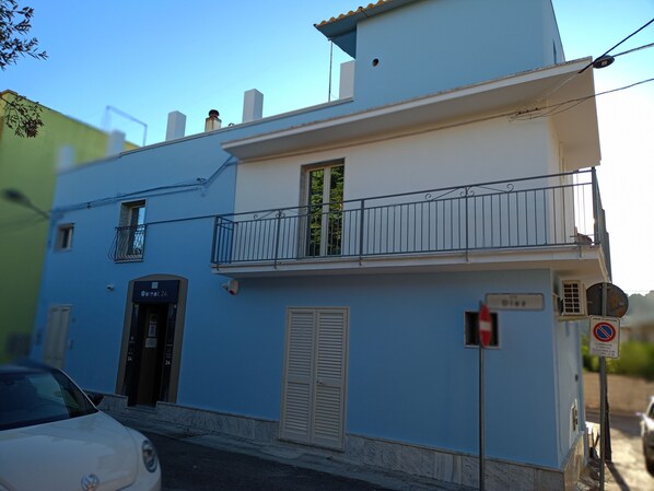 A two-story building with a balcony, a door with shutters, and a sign indicating no parking.