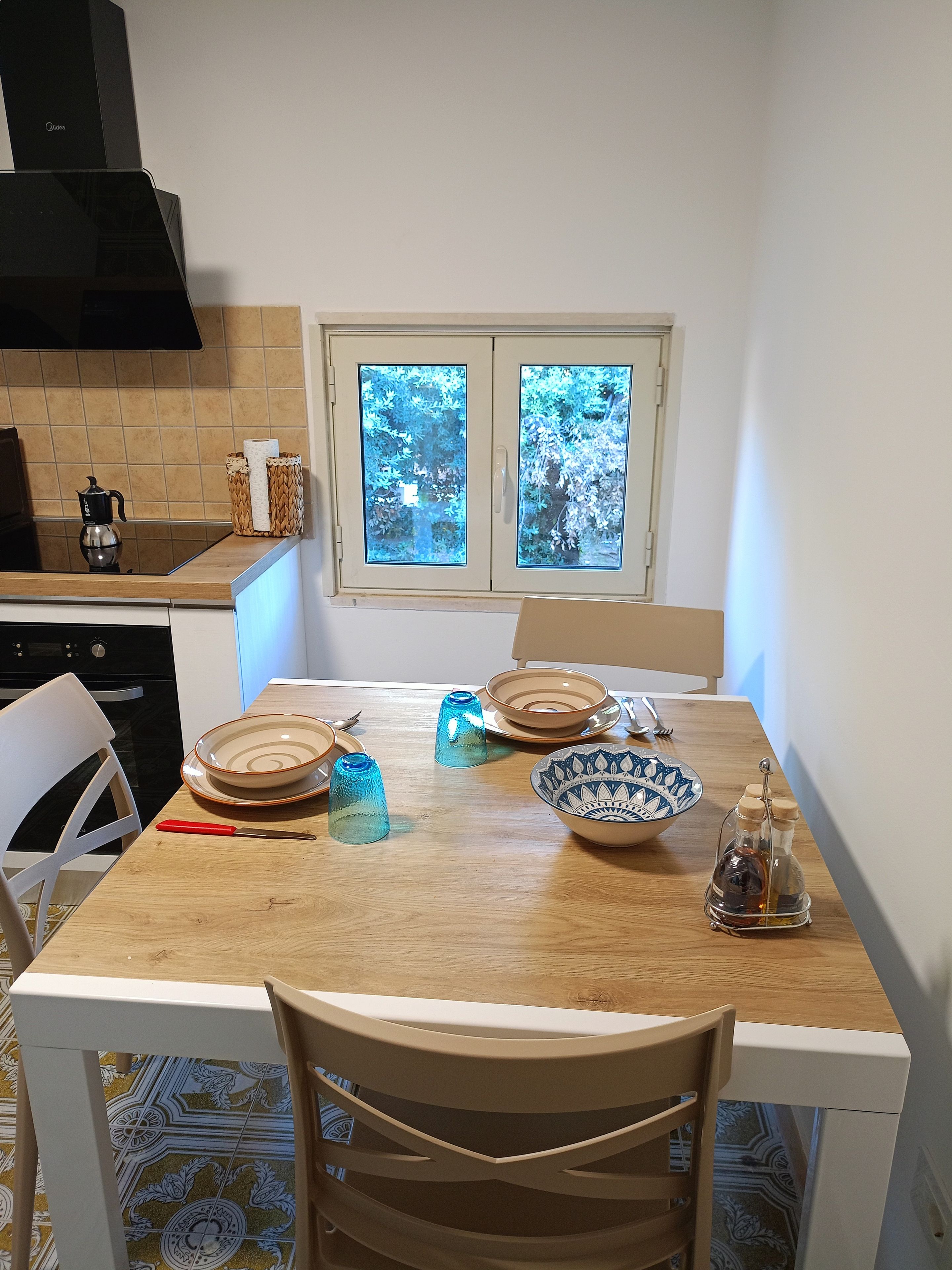 Una cocina con una mesa de comedor, sillas y un ventanal con vistas a árboles.