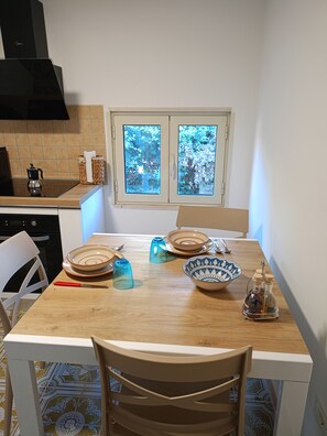 Una cocina con una mesa de comedor, sillas y un ventanal con vistas a árboles.