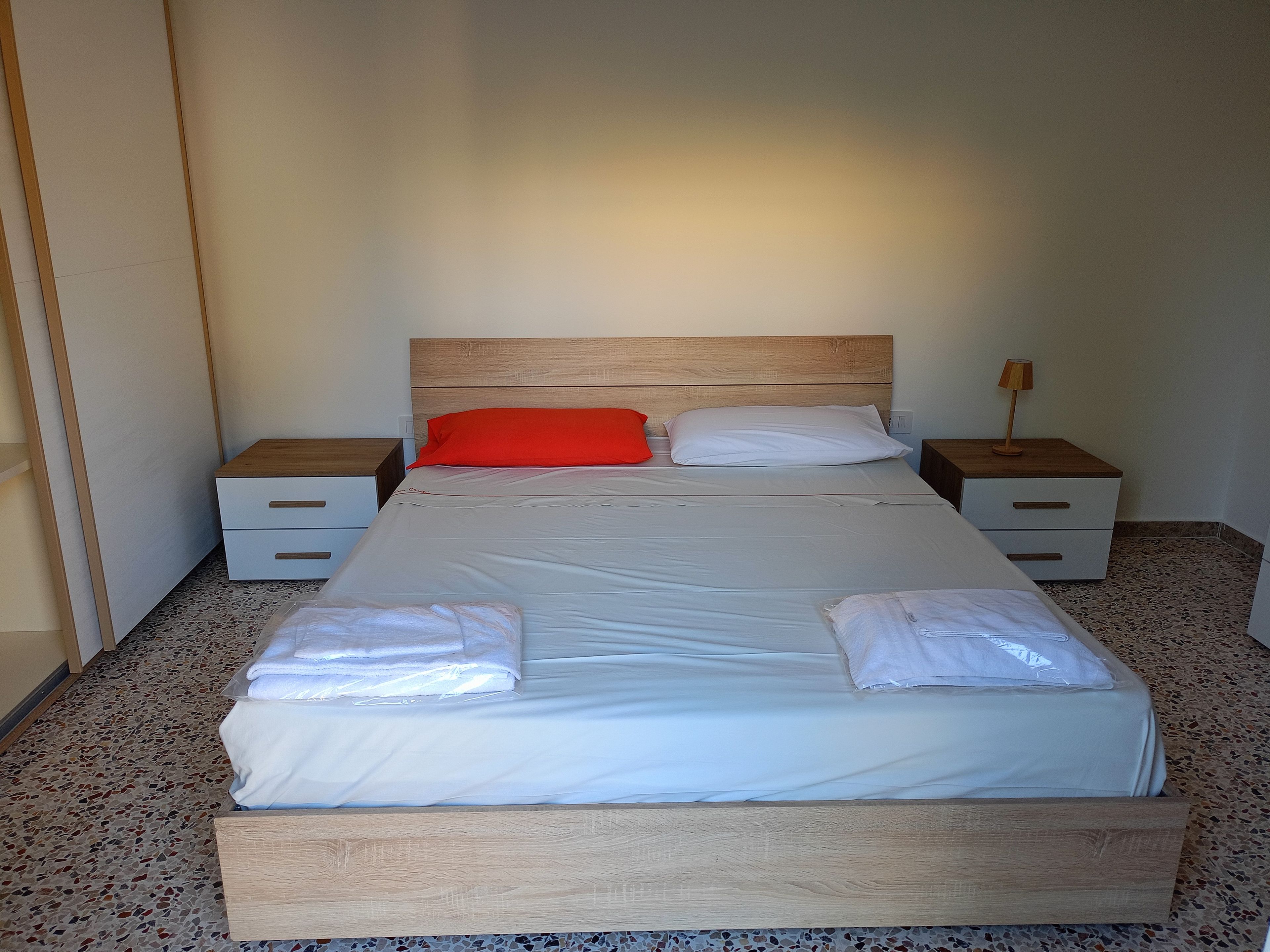Un letto con una testiera in legno, due comodini e una lampada.
