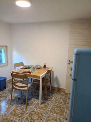 Uma área de refeições com uma mesa de madeira, cadeiras e uma geladeira azul.