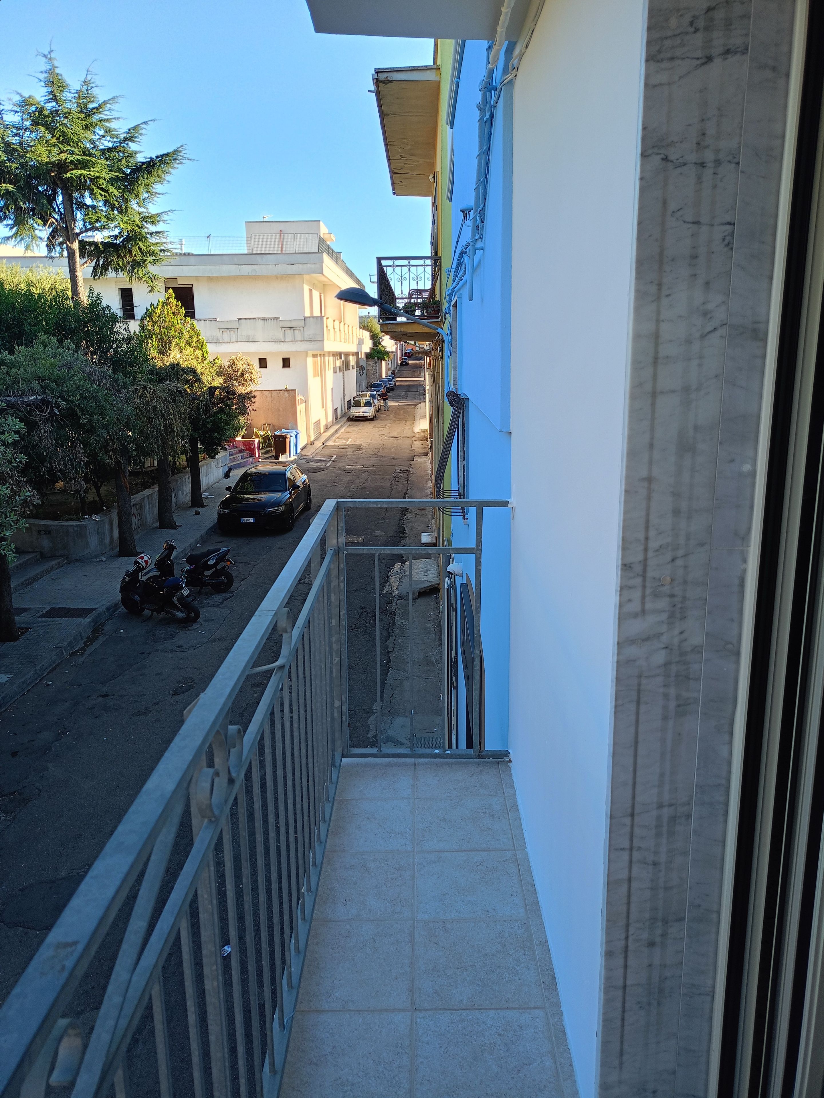 A narrow alleyway with parked motorcycles and a row of parked cars.