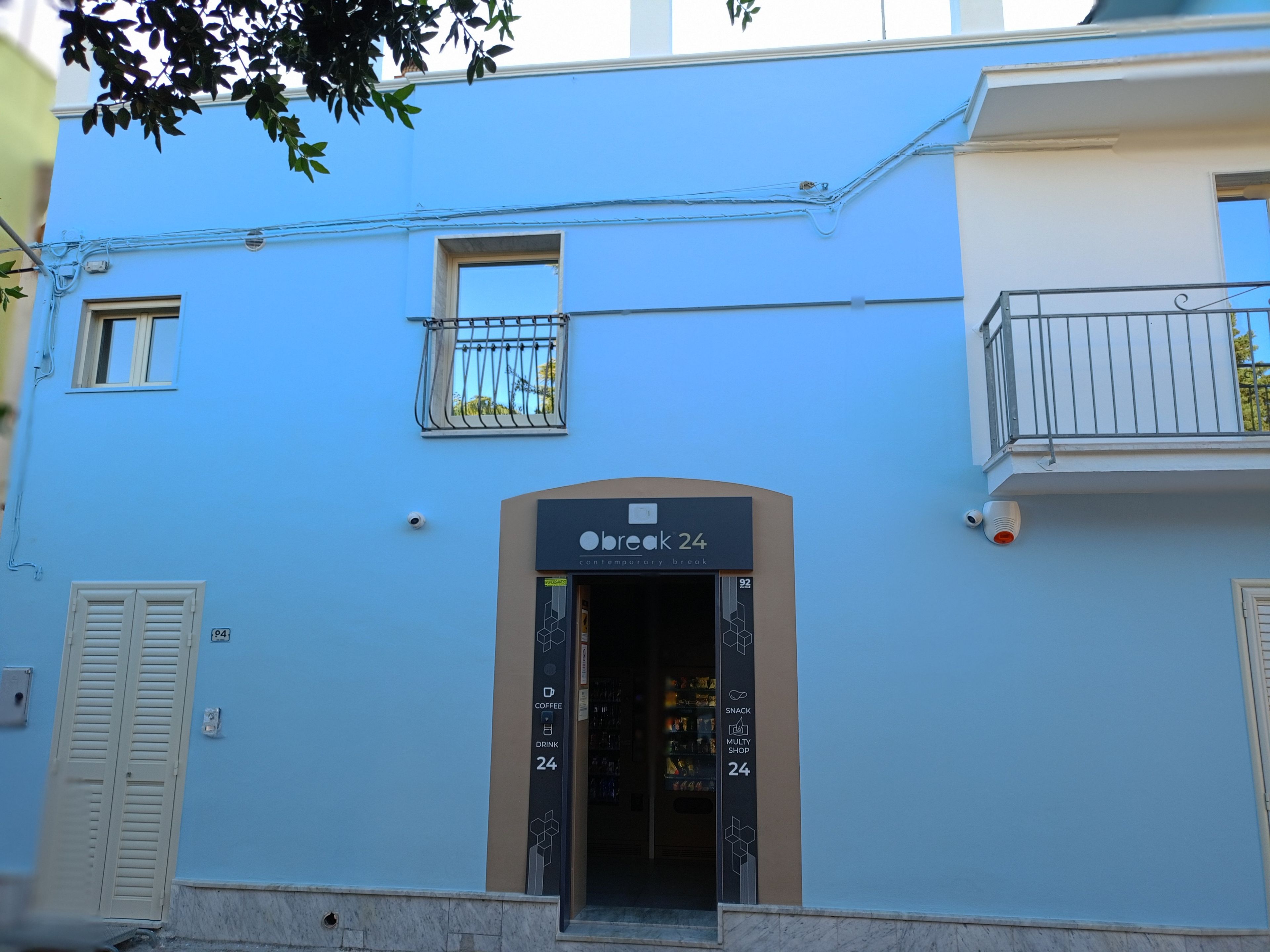 Un edificio con fachada azul, un cartel que dice 'Obreac 24 contemporary break' y una entrada visible.