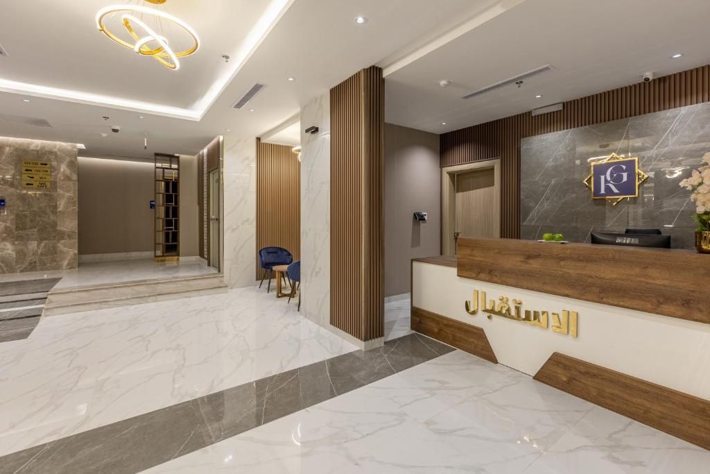 Zona de recepción de hotel con suelo de mármol, mostrador y pared de paneles de madera.