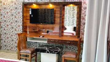 Un dormitorio con un escritorio de madera, un televisor y una cama con papel tapiz floral.