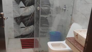 Un baño con cabina de ducha de vidrio, inodoro y zona de lavamanos.