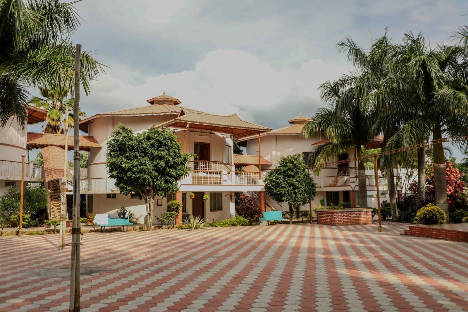 A multi-story building with a central courtyard, surrounded by palm trees and a patterned pavement.