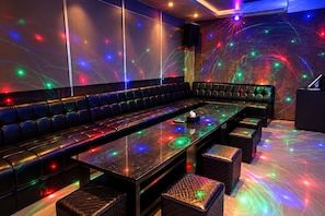 A lounge area with a long table, cushioned seating, and a speaker.
