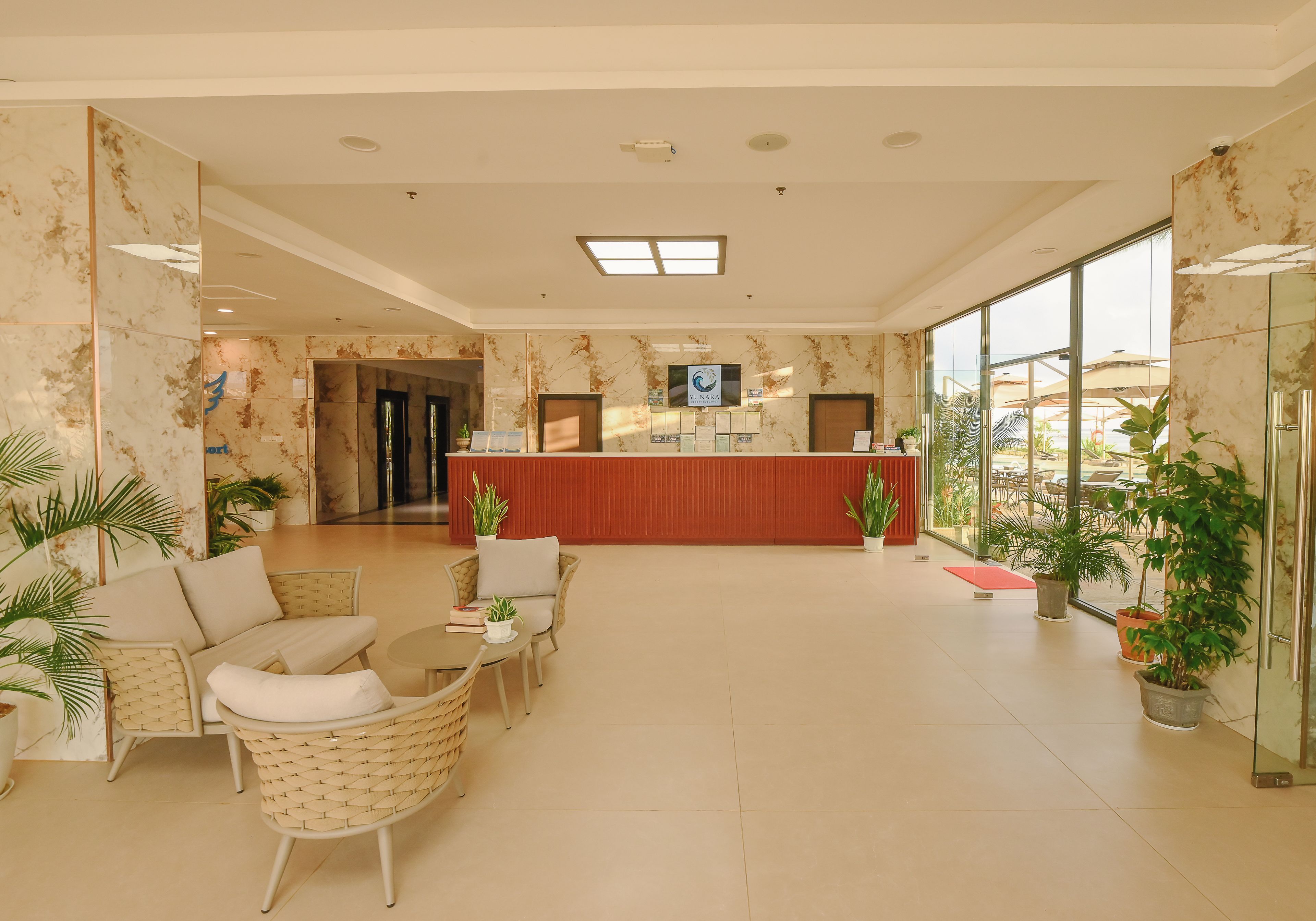 A hotel lobby with a reception desk, seating area, and large windows.
